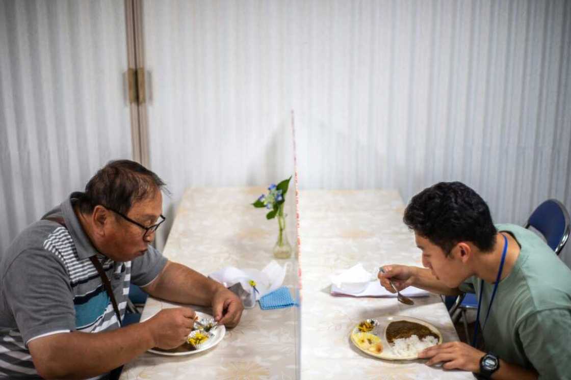 Koichi Miyatsu (R) and his adoptive father Yoshimitsu eat curry together after their monthly charity event at a church in Kumamoto Koichi Miyatsu (R) and his adoptive father Yoshimitsu eat curry together after their monthly charity event at a church in Kumamoto
