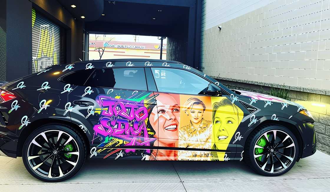 A black Lamborghini Urus with custom wrap that features JoJo Siwa's face A black Lamborghini Urus with custom wrap that features JoJo Siwa's face
