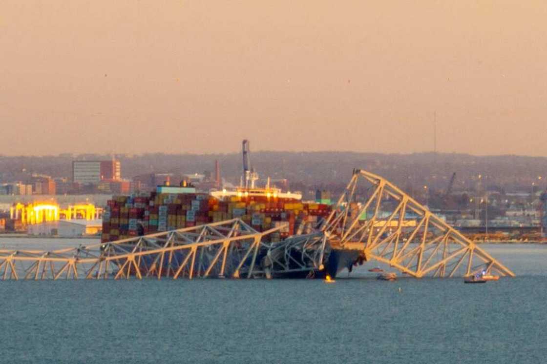 The steel frame of the Francis Scott Key Bridge sits on top of a container ship after it struck the bridge in Baltimore, Maryland, on March 26, 2024