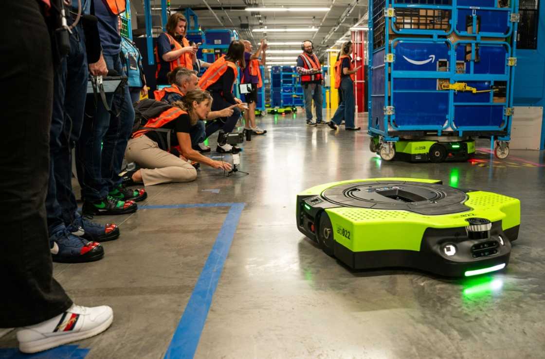 Amazon says logistics center automation, such as robots that safely maneuver loaded carts to waiting trucks, can free human workers for more interesting tasks