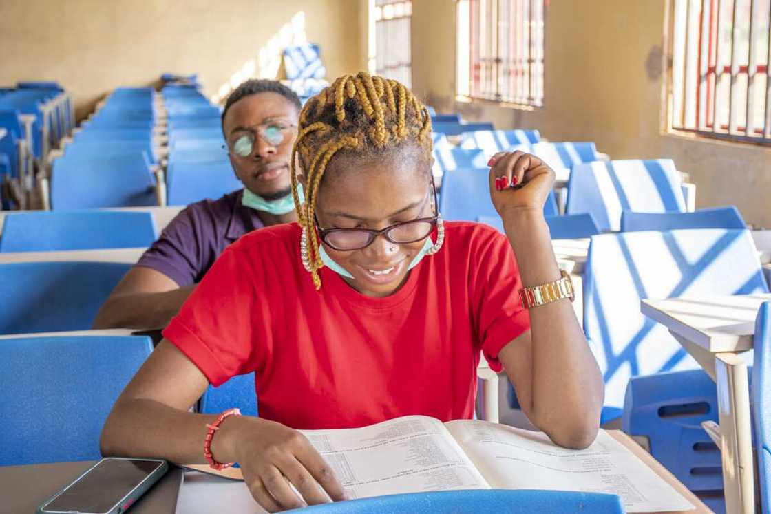 Two young students wearing facemasks and studying in a classroom Two young students wearing facemasks and studying in a classroom