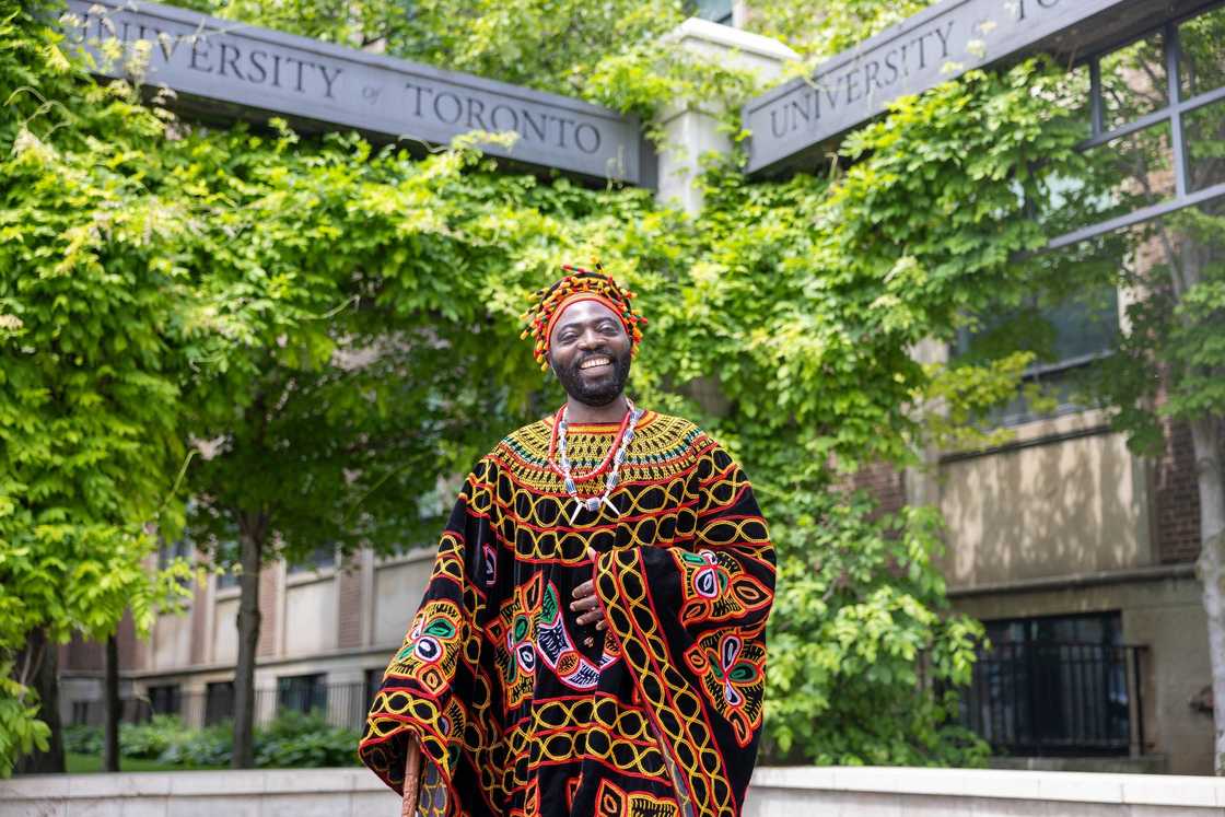 An African student in traditional attire posing for a photo