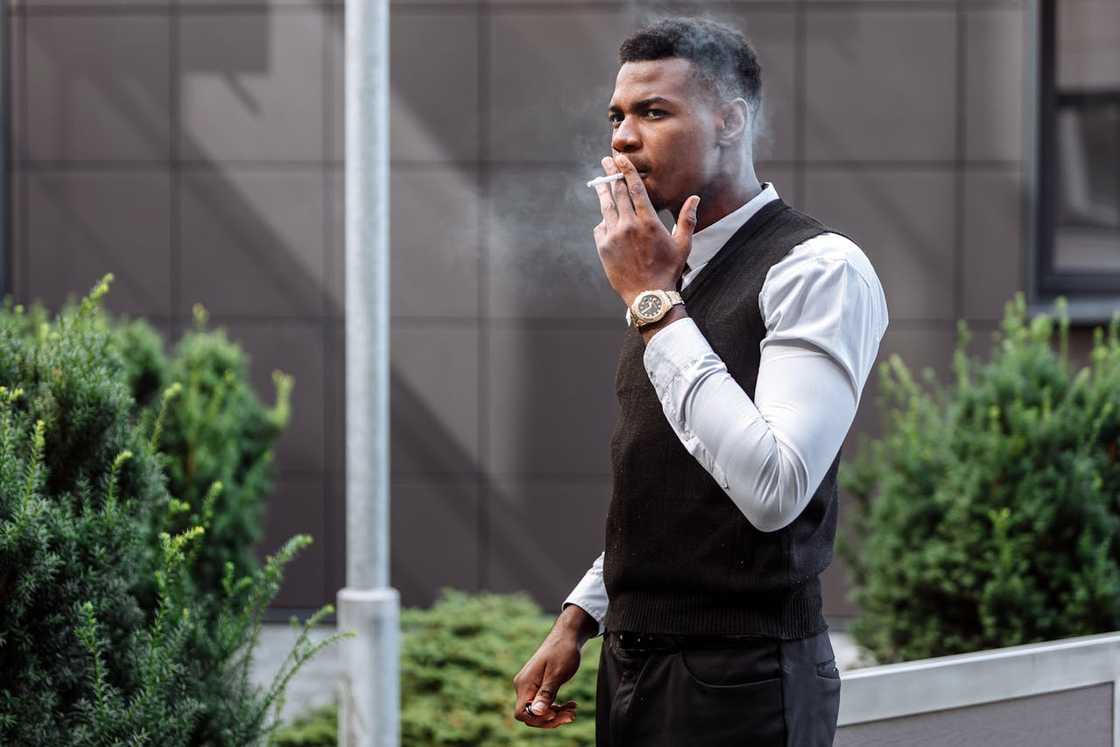 A man smokes outdoors, looking thoughtful. A man smokes outdoors, looking thoughtful.