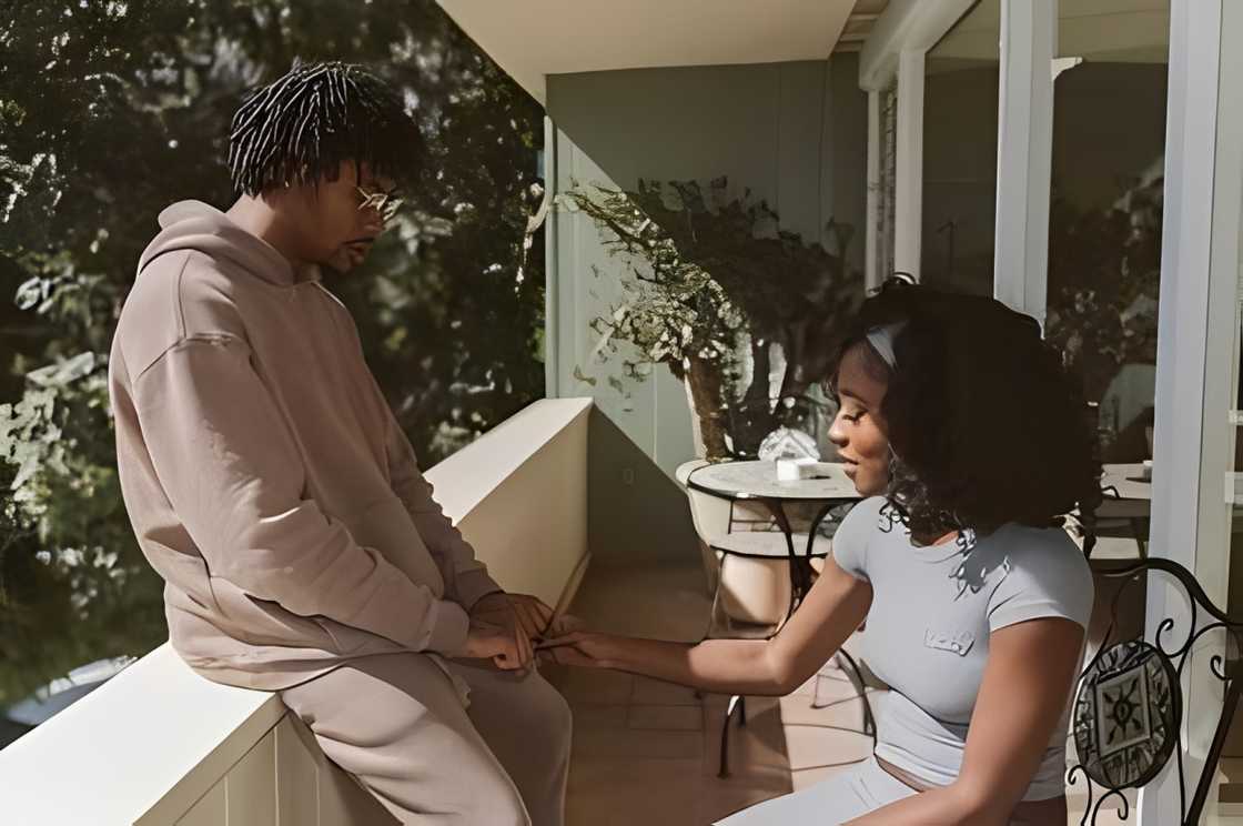 Serena and Kordell hold hands in a balcony