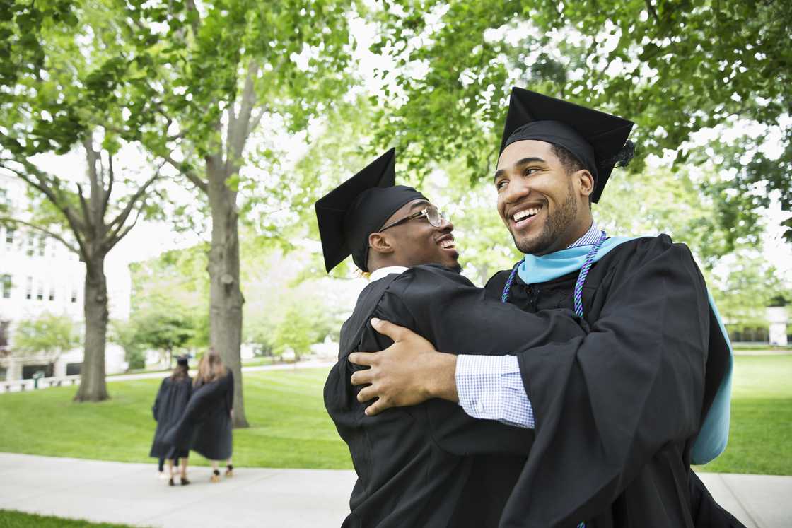 Graduates smile as they embrace each other during their graduation ceremony Graduates smile as they embrace each other during their graduation ceremony