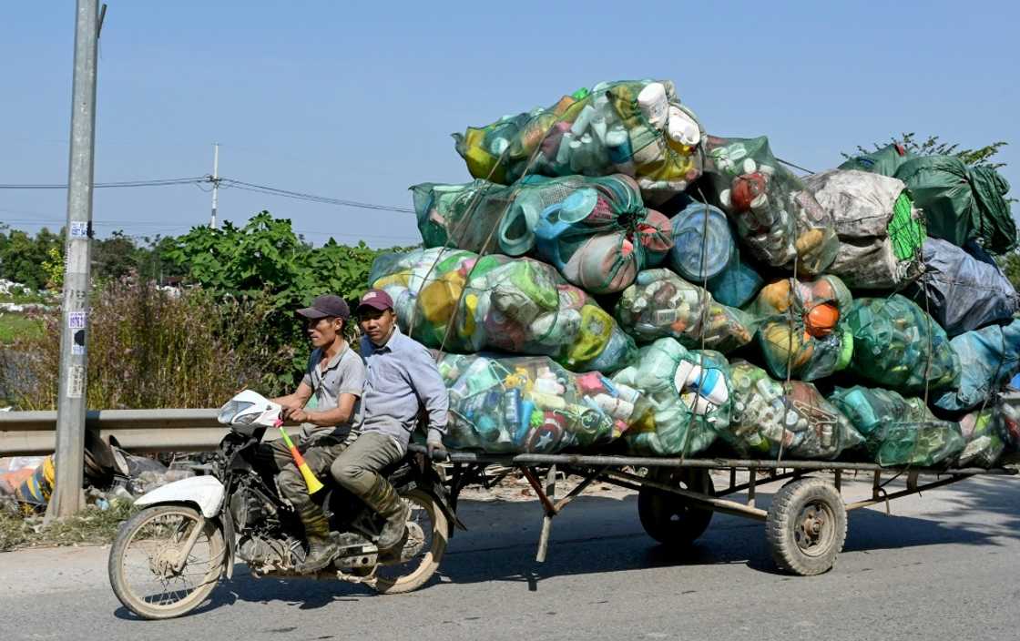 Men on a motorbike pull a cart carrying plastic waste on the outskirts of Hanoi Men on a motorbike pull a cart carrying plastic waste on the outskirts of Hanoi