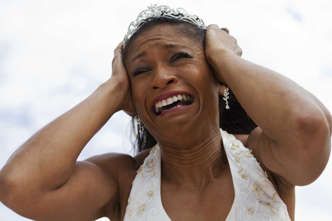A bride in a tiara holding her head in distress. A bride in a tiara holding her head in distress.