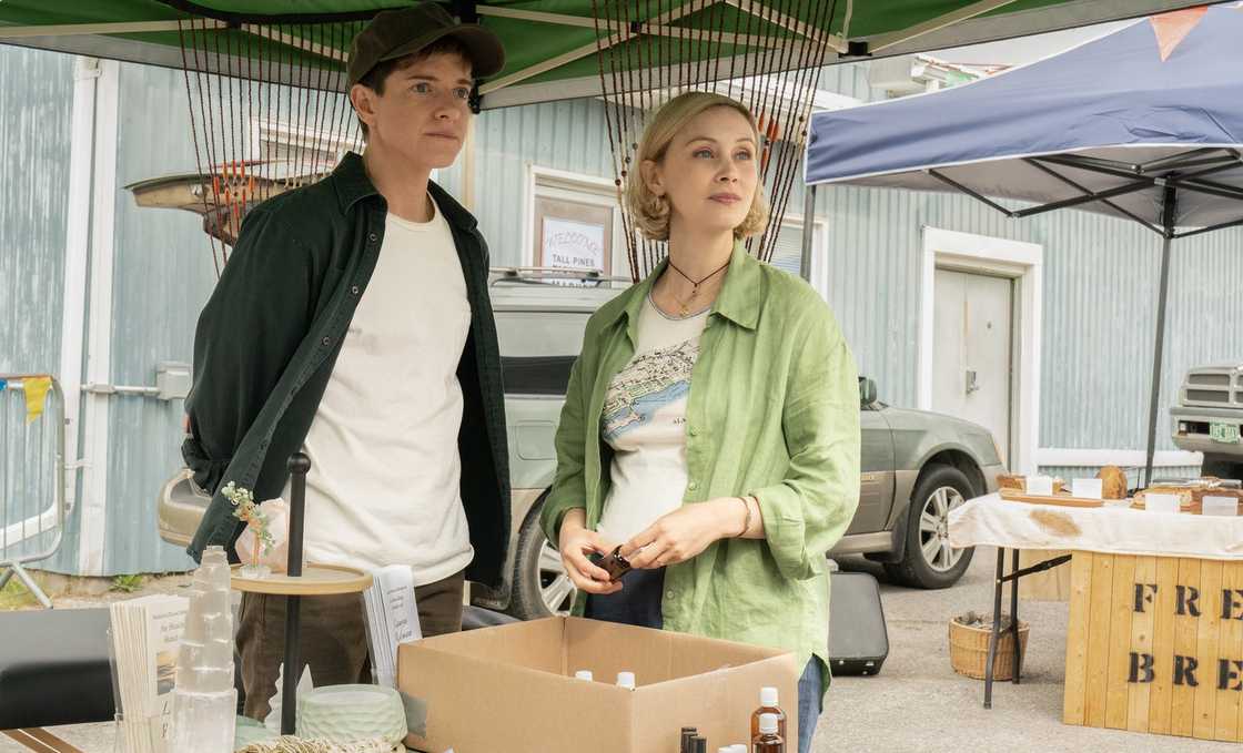 Alex and Laura, his pregnant wife look on a an outdoor yard sale