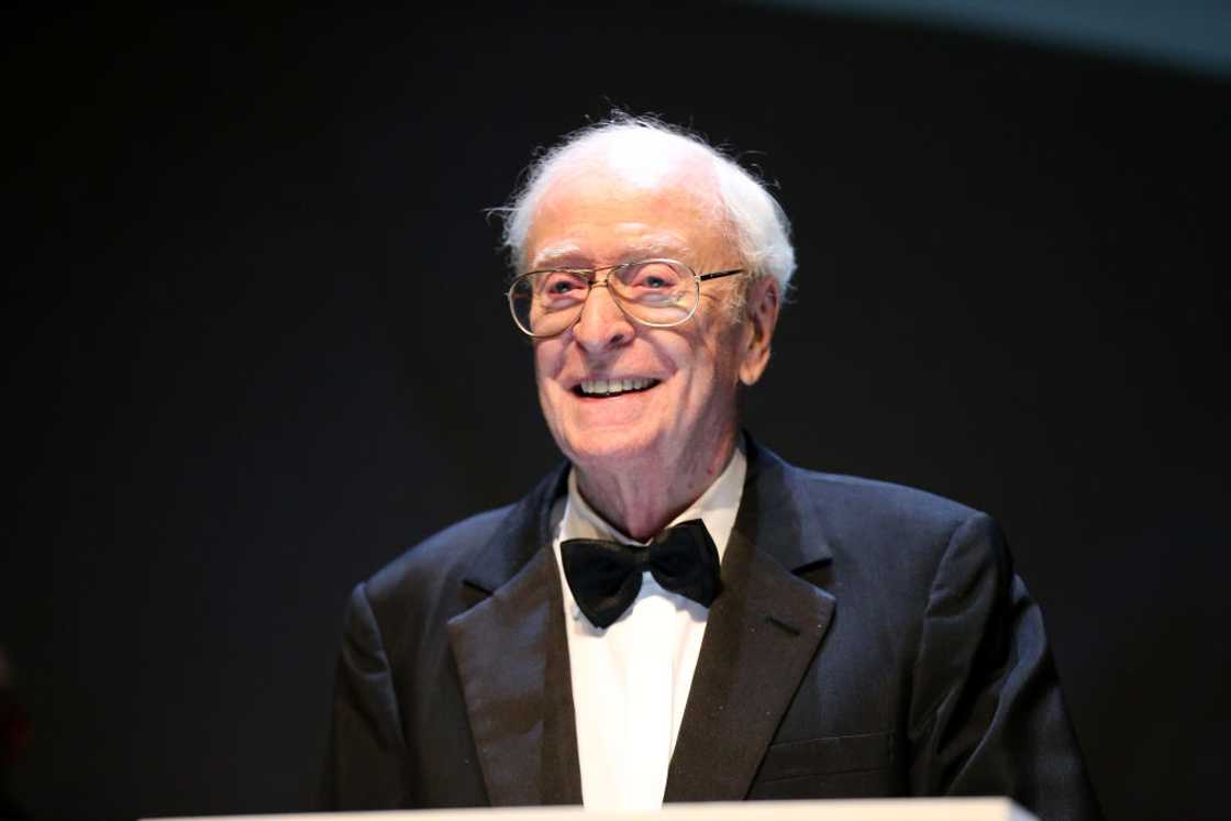 Sir Michael Caine on stage in a black suite and white shirt at the 55th Karlovy Vary International Film Festival