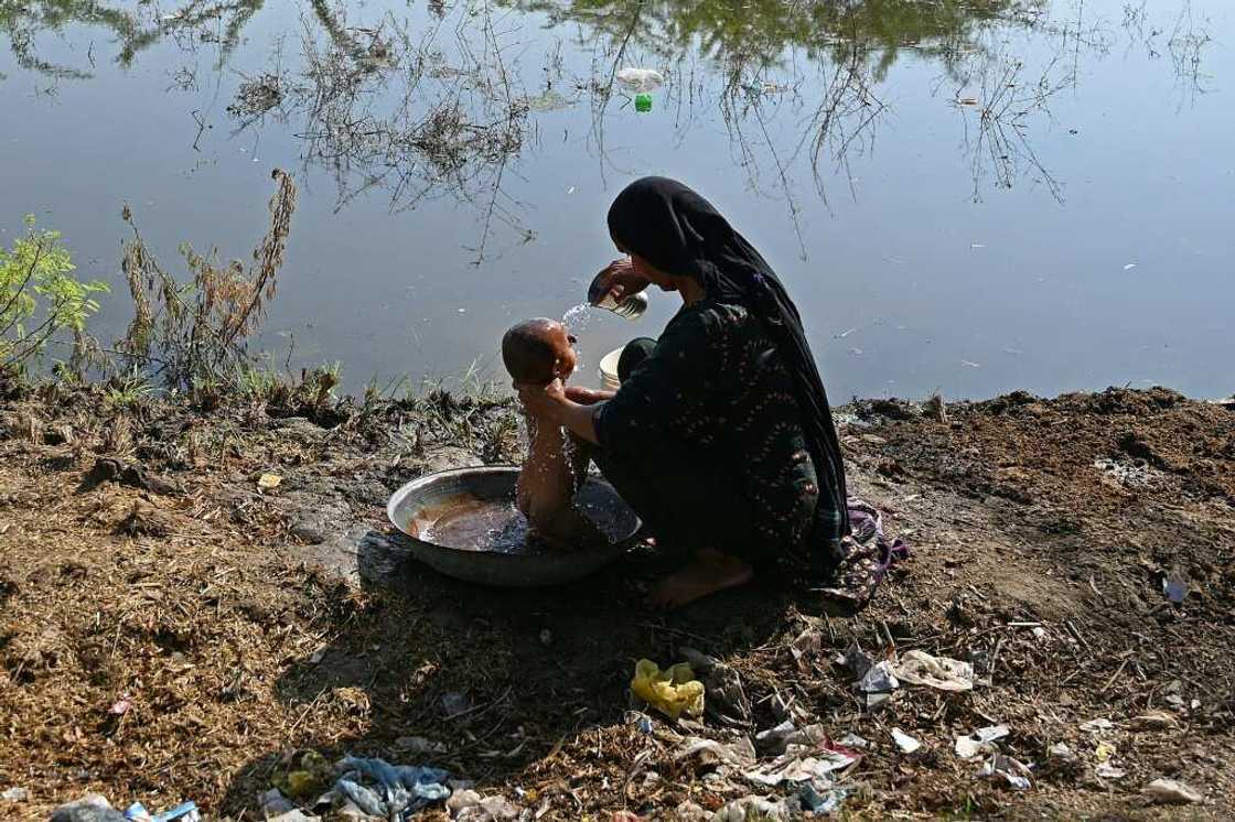 A woman bathes her child next to a flooded field in southern Pakistan A woman bathes her child next to a flooded field in southern Pakistan
