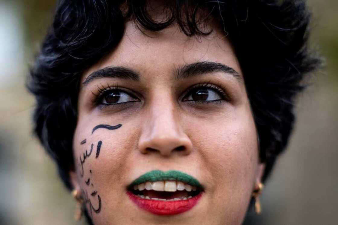 A woman wearing lipsticks in the colours of the Iranian flag takes part in a rally in support of protests in Iran in Paris