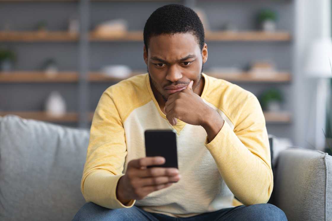 A young man stares at his phone