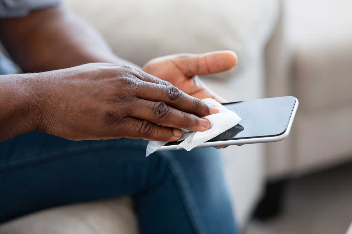 A man cleaning a smartphone screen. A man cleaning a smartphone screen.