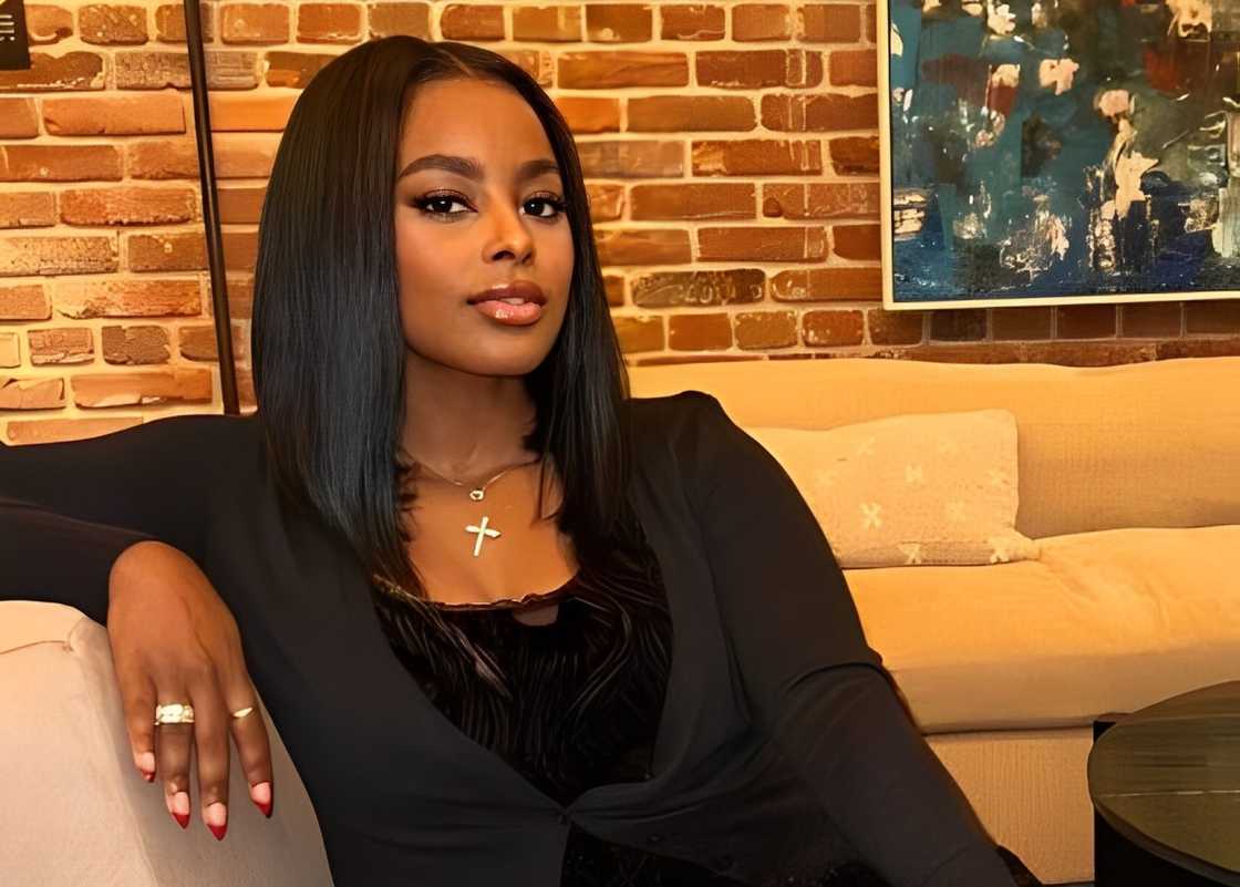 Ashley posing in a black outfit on a couch