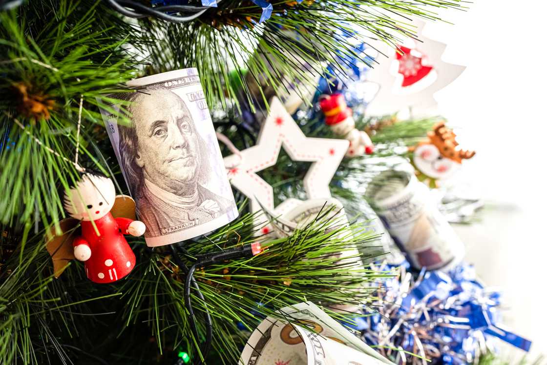 Dollar bills hanging on a Christmas tree alongside traditional Christmas decorations Dollar bills hanging on a Christmas tree alongside traditional Christmas decorations