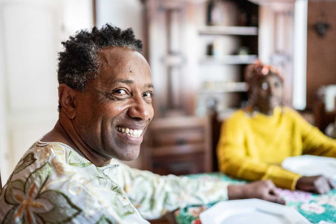 Two people sit at a table in a home setting.