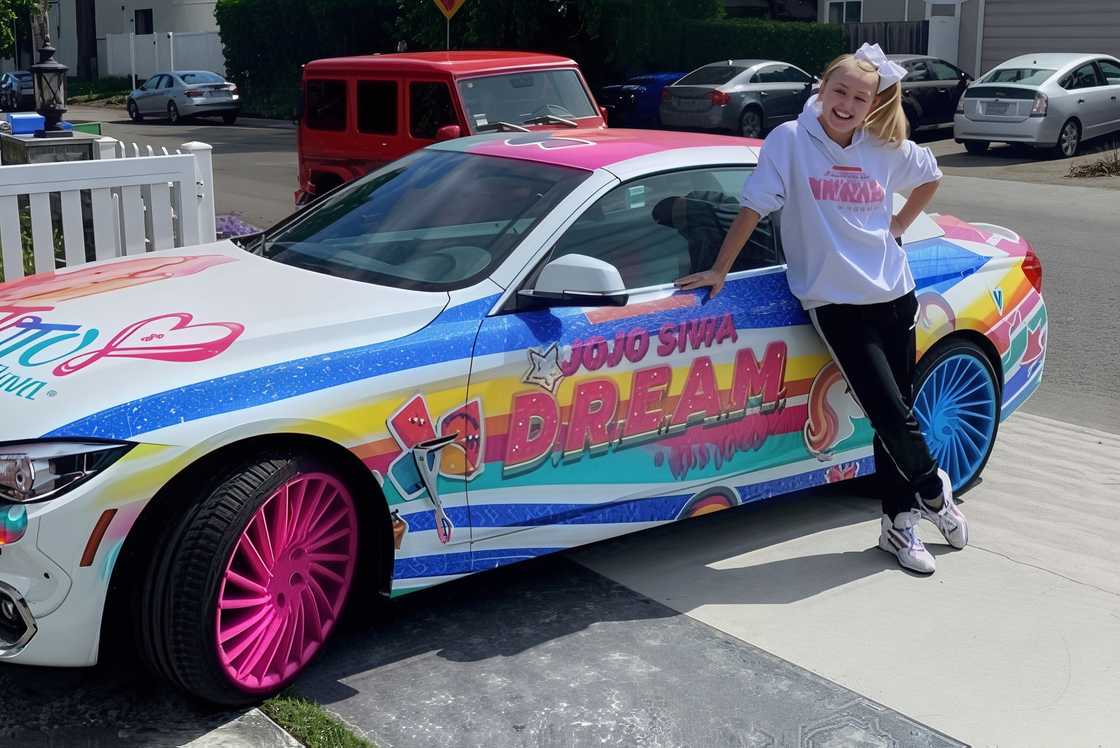 JoJo Siwa stands next to her custom wrapped BMW JoJo Siwa stands next to her custom wrapped BMW