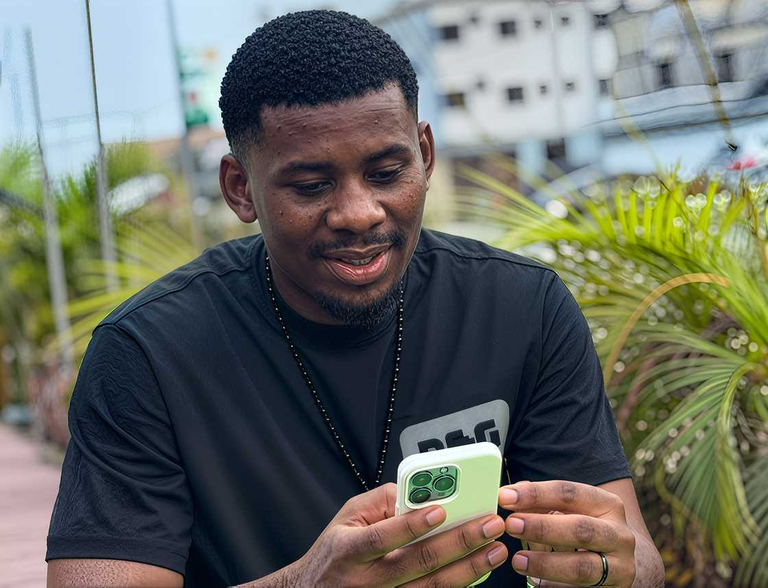 Victory Okokon scrolling through his phone outdoors
