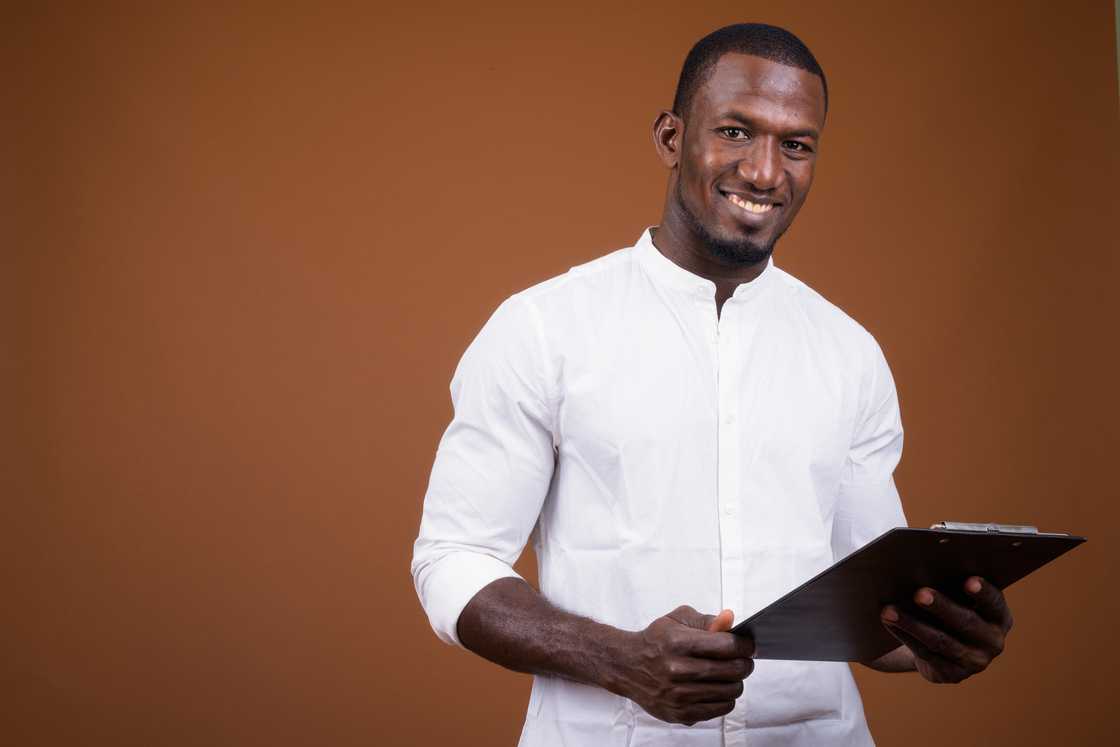 A man smiles while holding a document A man smiles while holding a document