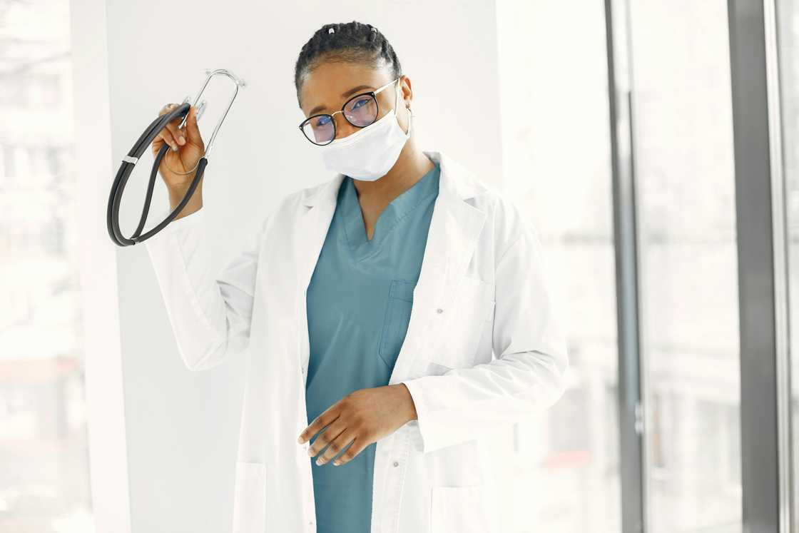 A health worker in a white lab gown holding a stethoscope A health worker in a white lab gown holding a stethoscope