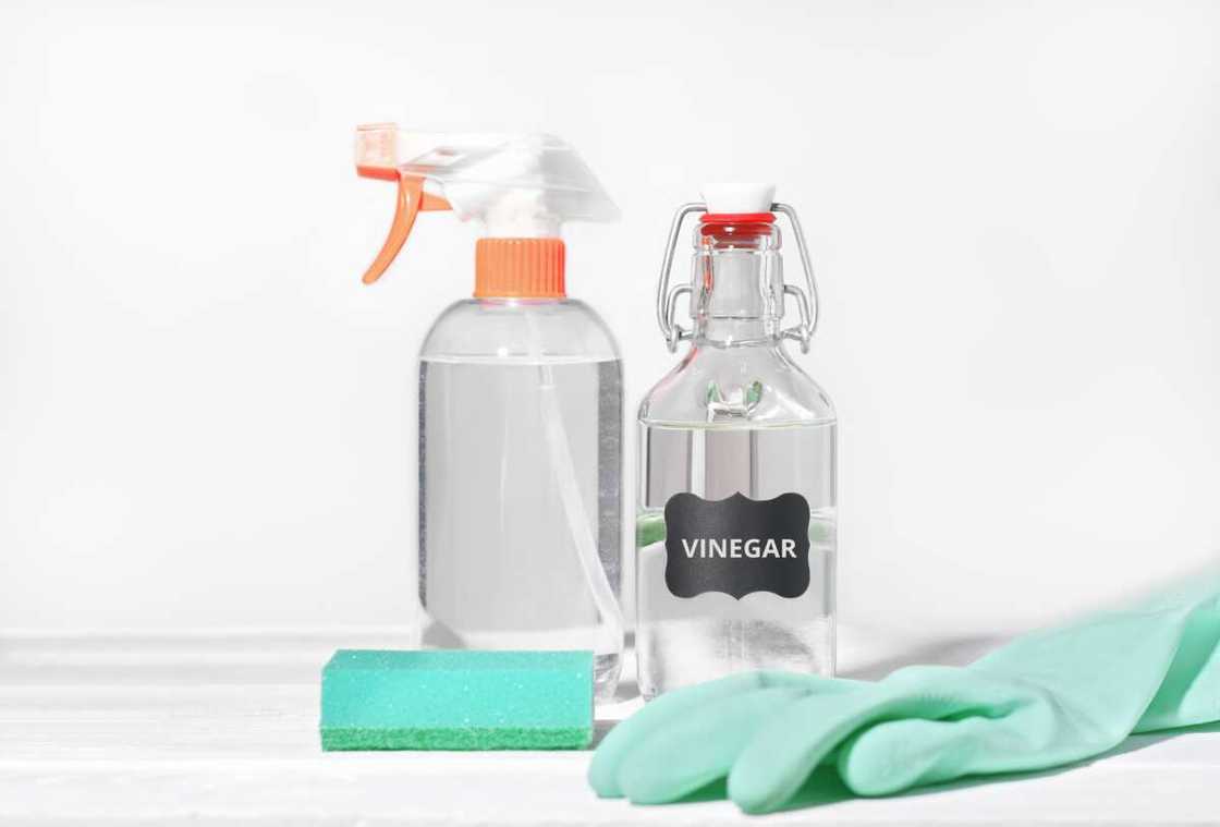 A clear spray bottle and a clear jar of vinegar