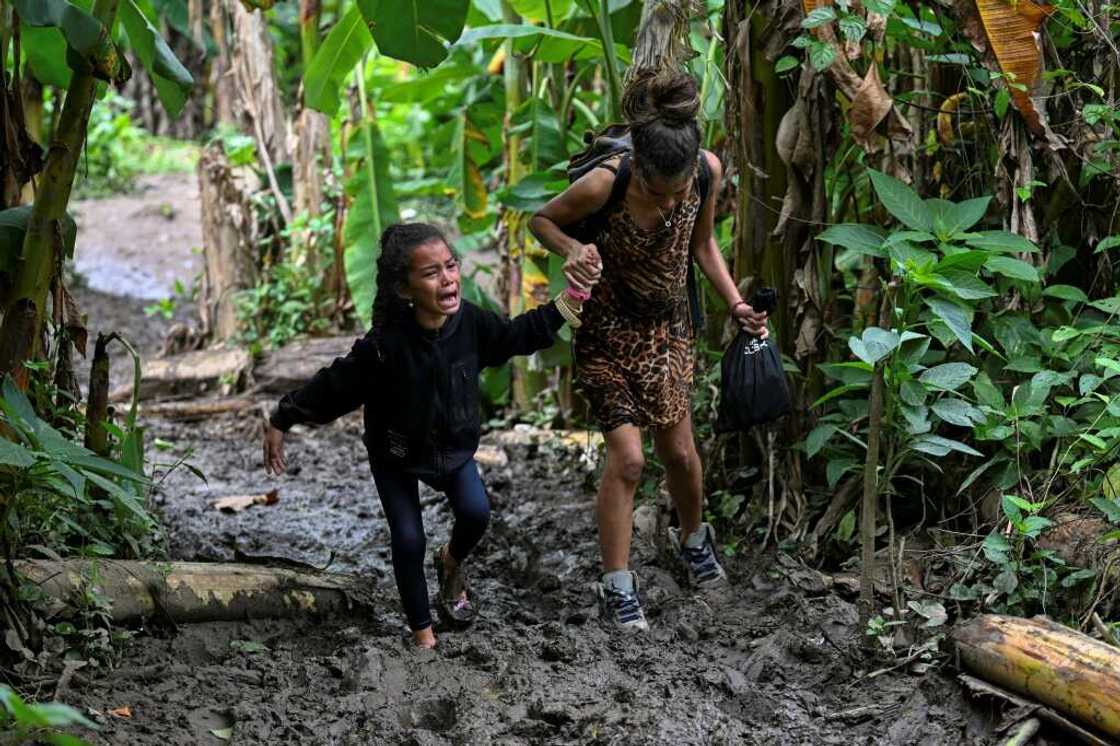 A Venezuelan migrant girl is helped by her mother as they arrive at Canaan Membrillo village in the Darien Jungle A Venezuelan migrant girl is helped by her mother as they arrive at Canaan Membrillo village in the Darien Jungle
