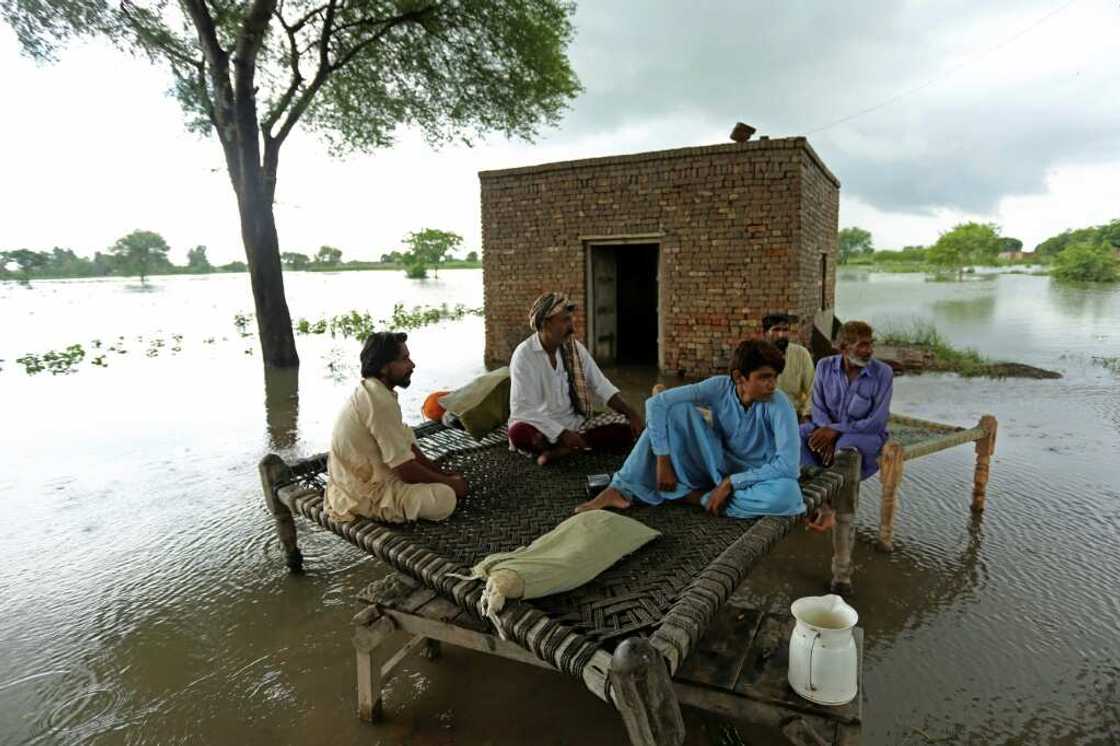 Rural residents sit on a tradional charpai bed in a flooded part of Rajanpur district Rural residents sit on a tradional charpai bed in a flooded part of Rajanpur district