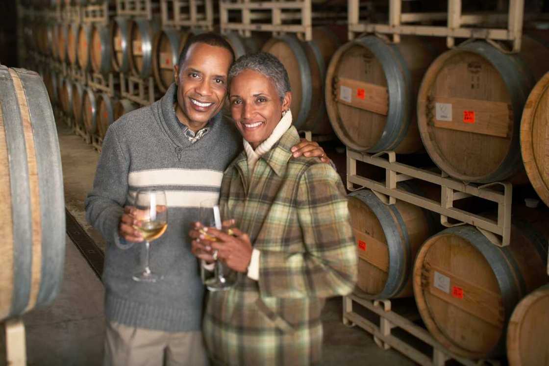 Mature couple tasting wine in cellar smiling