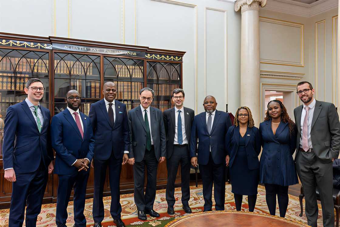 Treasury officials from Nigeria and England pose standing Treasury officials from Nigeria and England pose standing