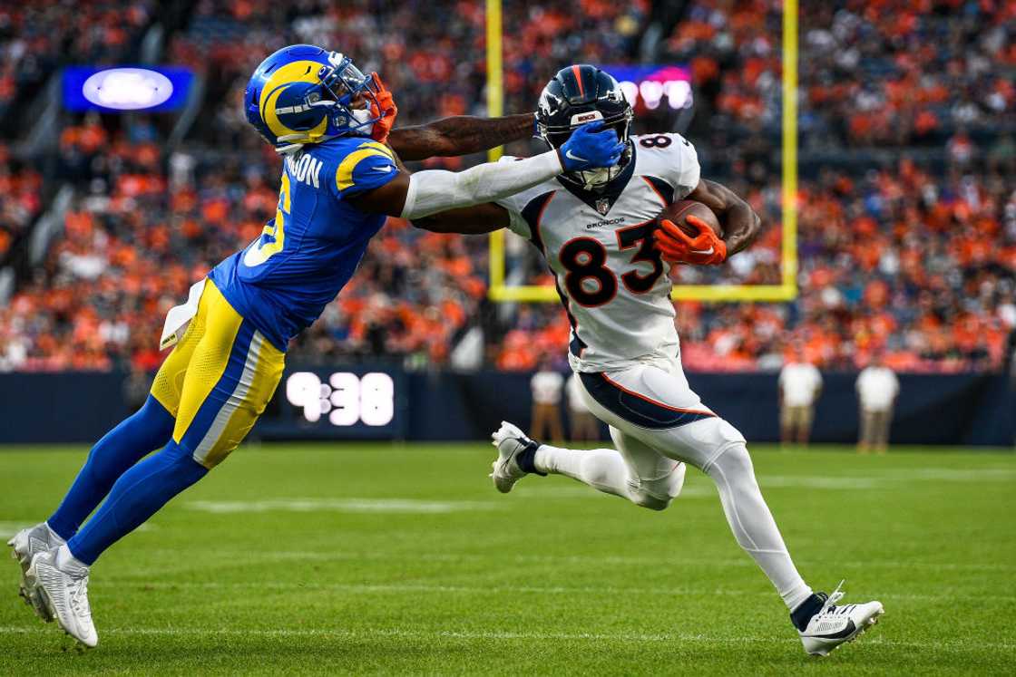 Marvin Mims Jr. #83 of the Denver Broncos is tackled by cornerback Tre Tomlinson #6 of the Los Angeles Rams on a play that would result in a face mask penalty