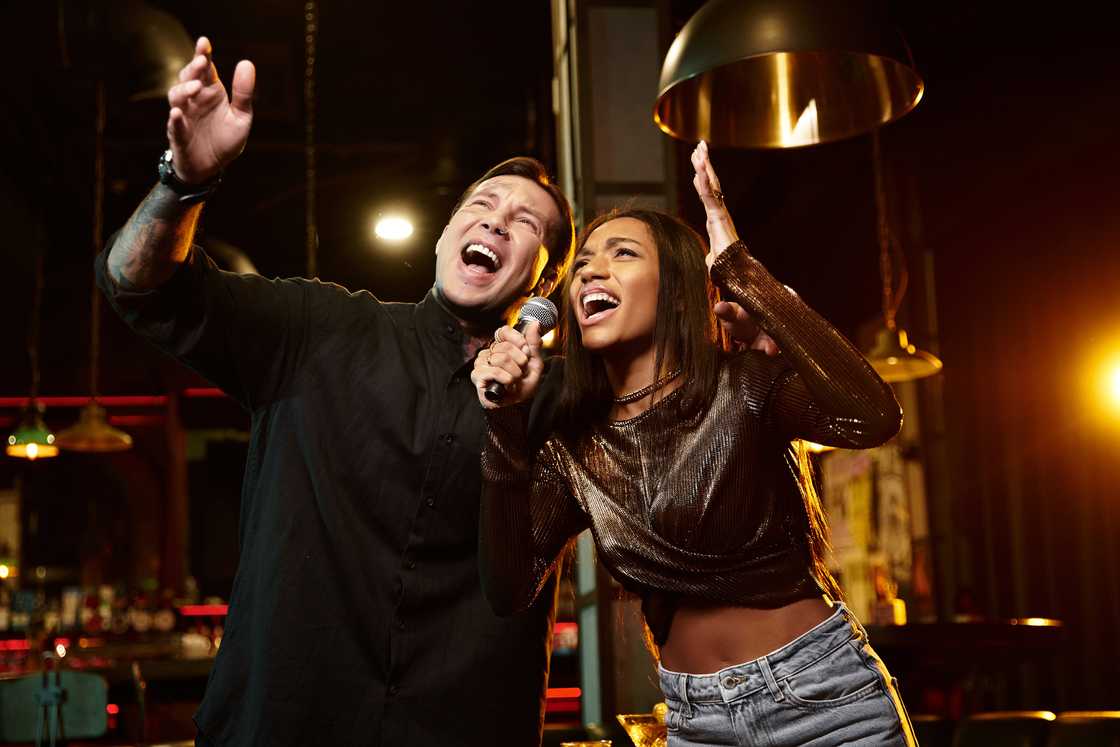 A young couple passionately sings together on stage in a lively bar. A young couple passionately sings together on stage in a lively bar.