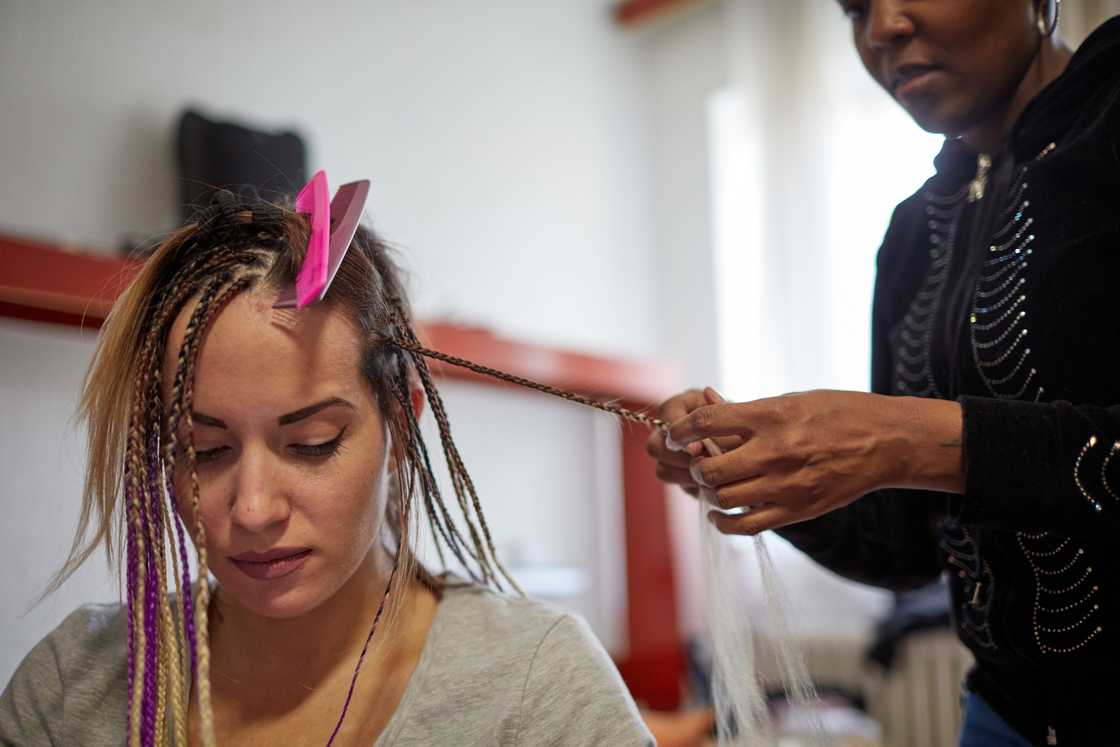 A lady at a salon threading a friend's hair