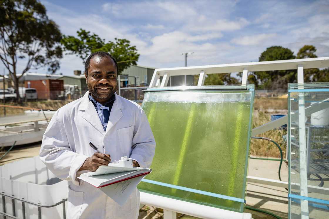 A front-view shot of a male scientist standing with a proud smile at a university