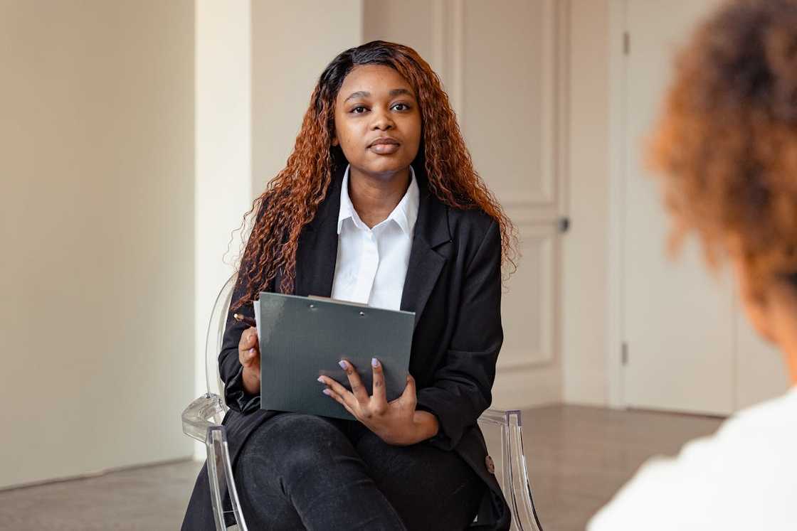 Woman holding a clipboard, listening attentively during a meeting. Woman holding a clipboard, listening attentively during a meeting.