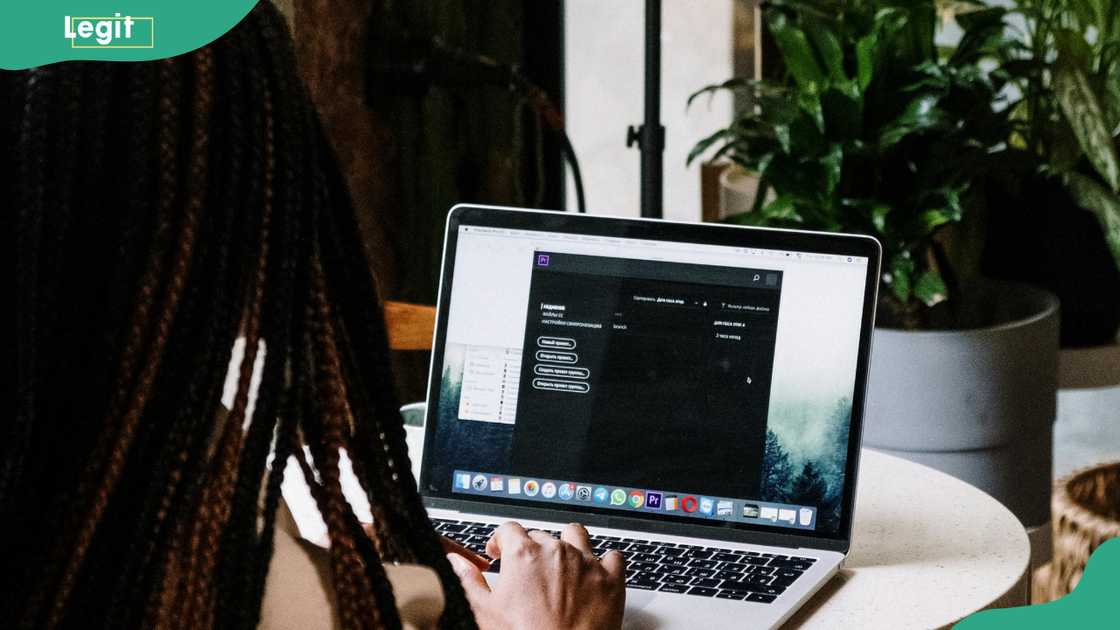 A person using Macbook Pro on a brown wooden table