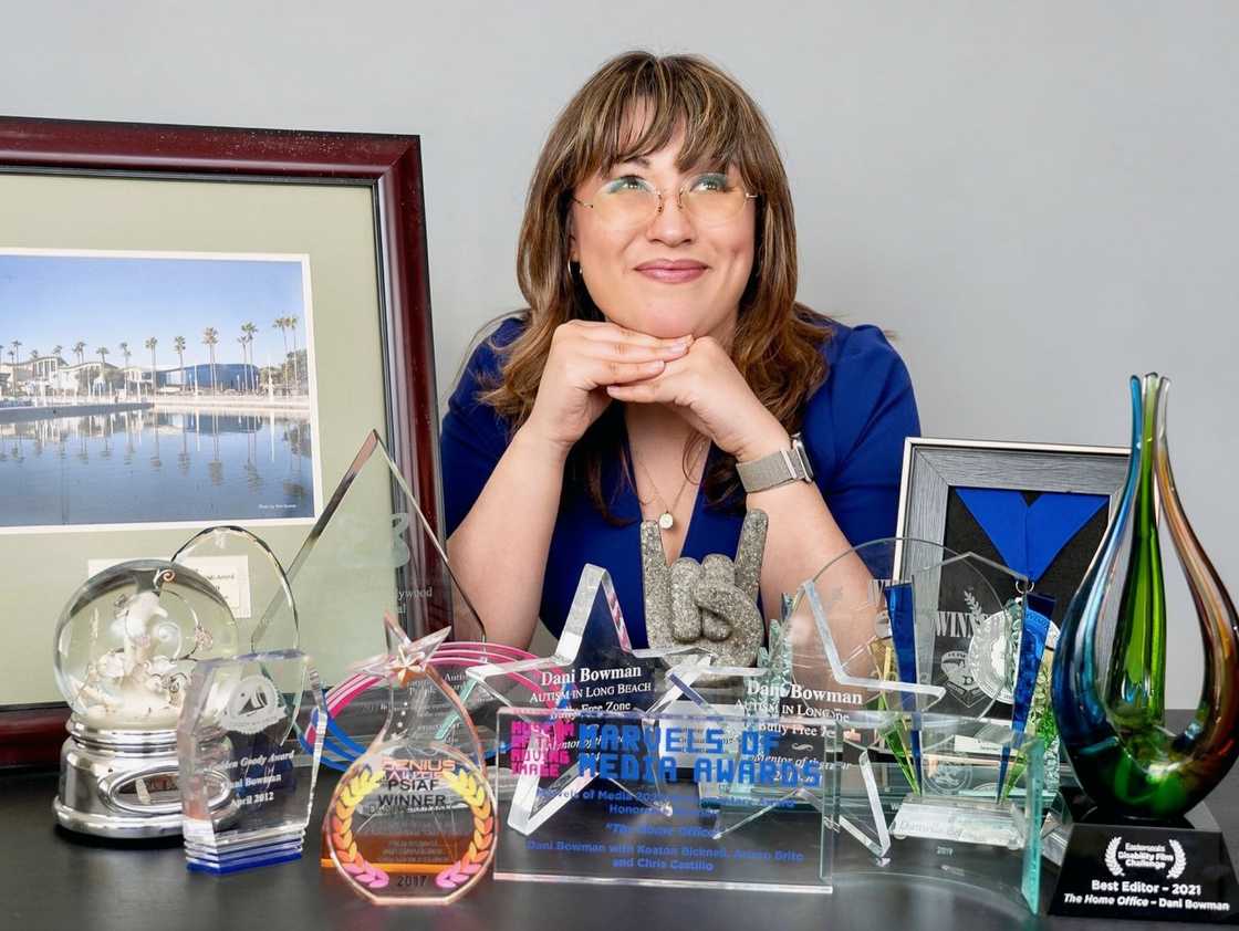Dani Bowman sits behind a desk with numerous glass and crystal awards. Dani Bowman sits behind a desk with numerous glass and crystal awards.
