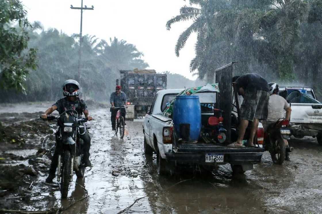 Residents leave their homes in the municipality of El Progreso, Honduras under pouring rain on October 8, 2022 before the arrival of Hurricane Julia