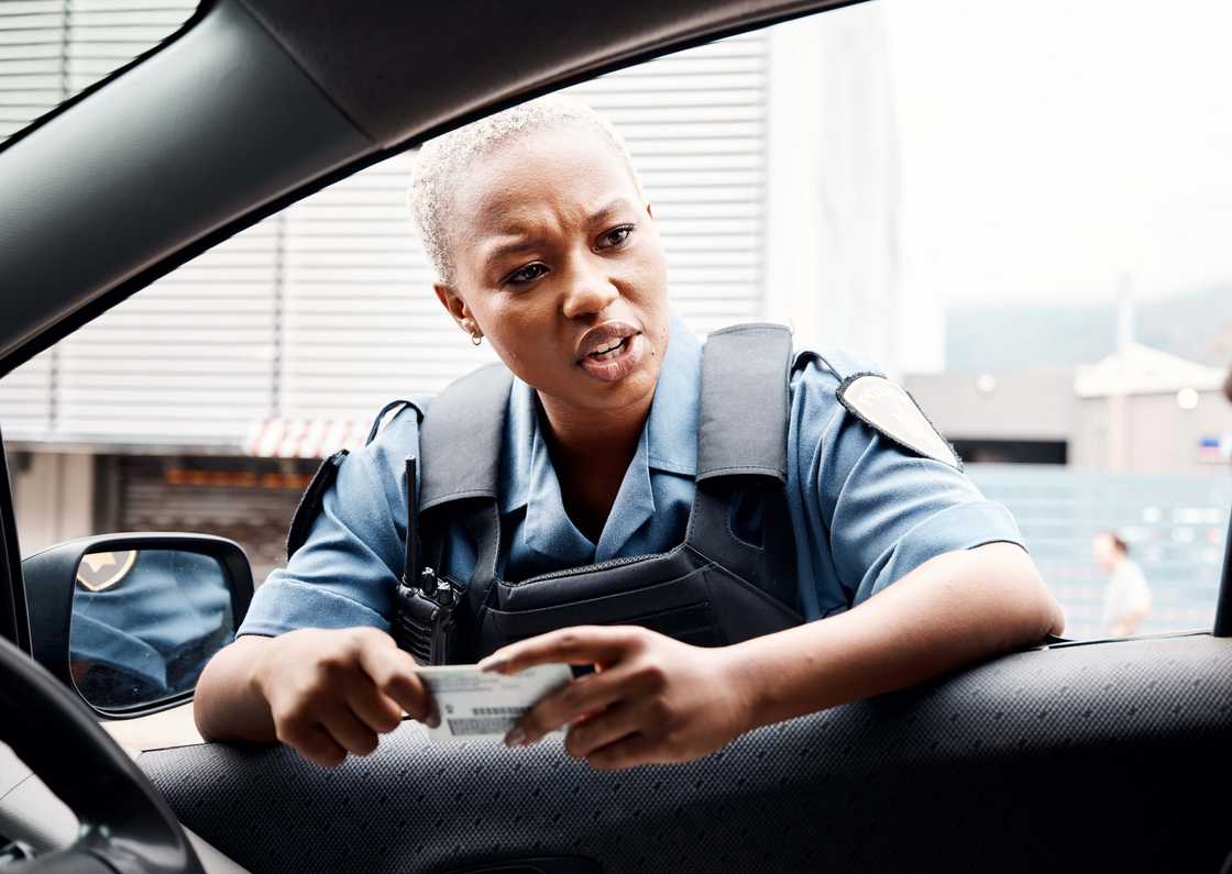 A police officer in the city talking to a driver who has violated law enforcement
