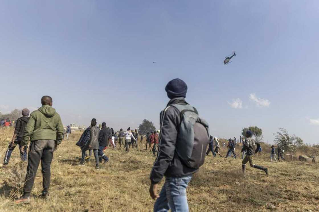 Residents run away from a police helicopter during a protest against illegal mining and rising crime in Kagiso Residents run away from a police helicopter during a protest against illegal mining and rising crime in Kagiso