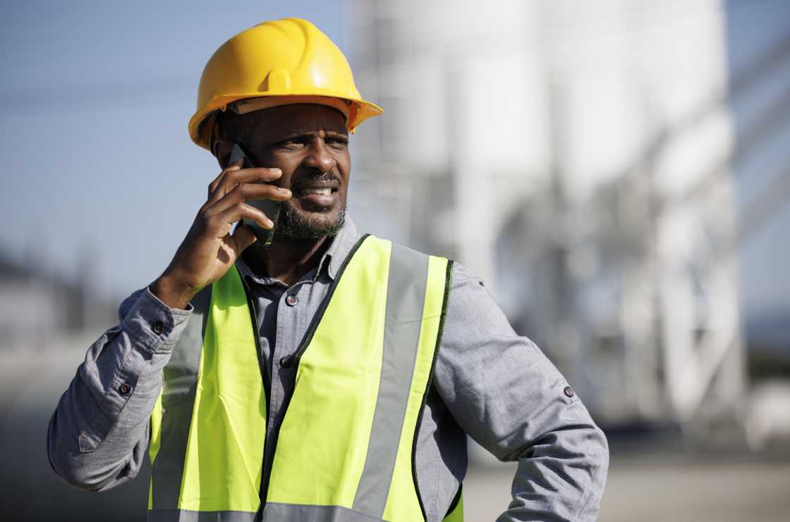 A construction worker with hardhat talking on mobile phone