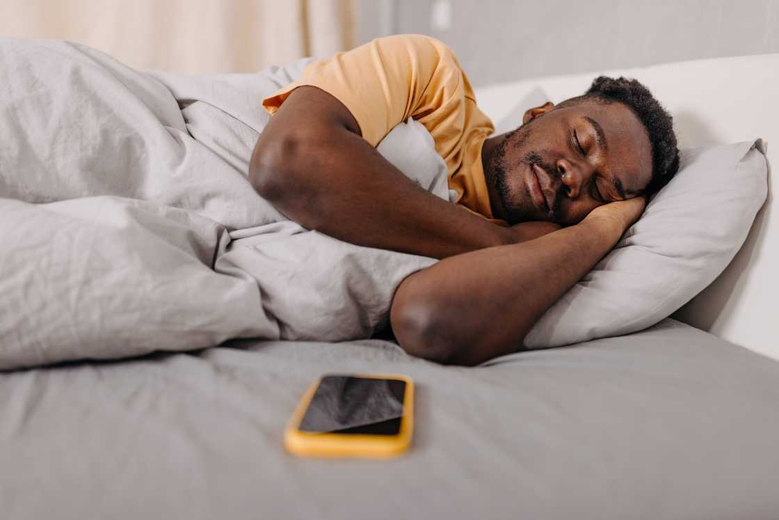 A man in yellow T-shirt sleeping on bed A man in yellow T-shirt sleeping on bed