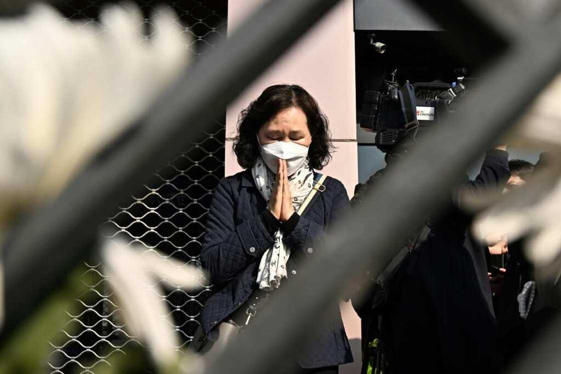 A woman prays in tribute to those who were killed in Seoul's Itaewon district during a Halloween crush at a makeshift memorial