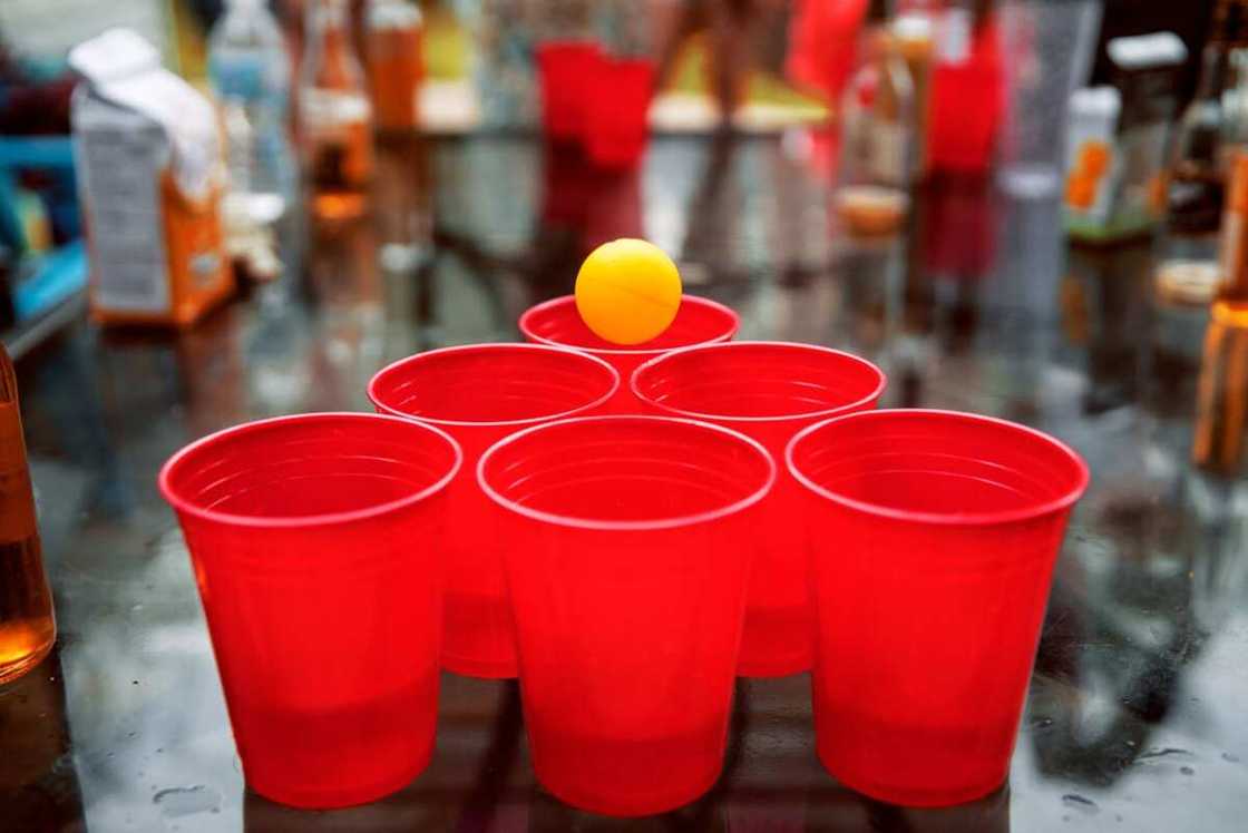 Party cups with a small yellow ball on the surface Party cups with a small yellow ball on the surface