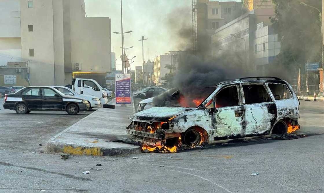 Damaged vehicles are pictured on a street in the Libyan capital Tripoli on August 27, 2022, following clashes between rival Libyan groups Damaged vehicles are pictured on a street in the Libyan capital Tripoli on August 27, 2022, following clashes between rival Libyan groups