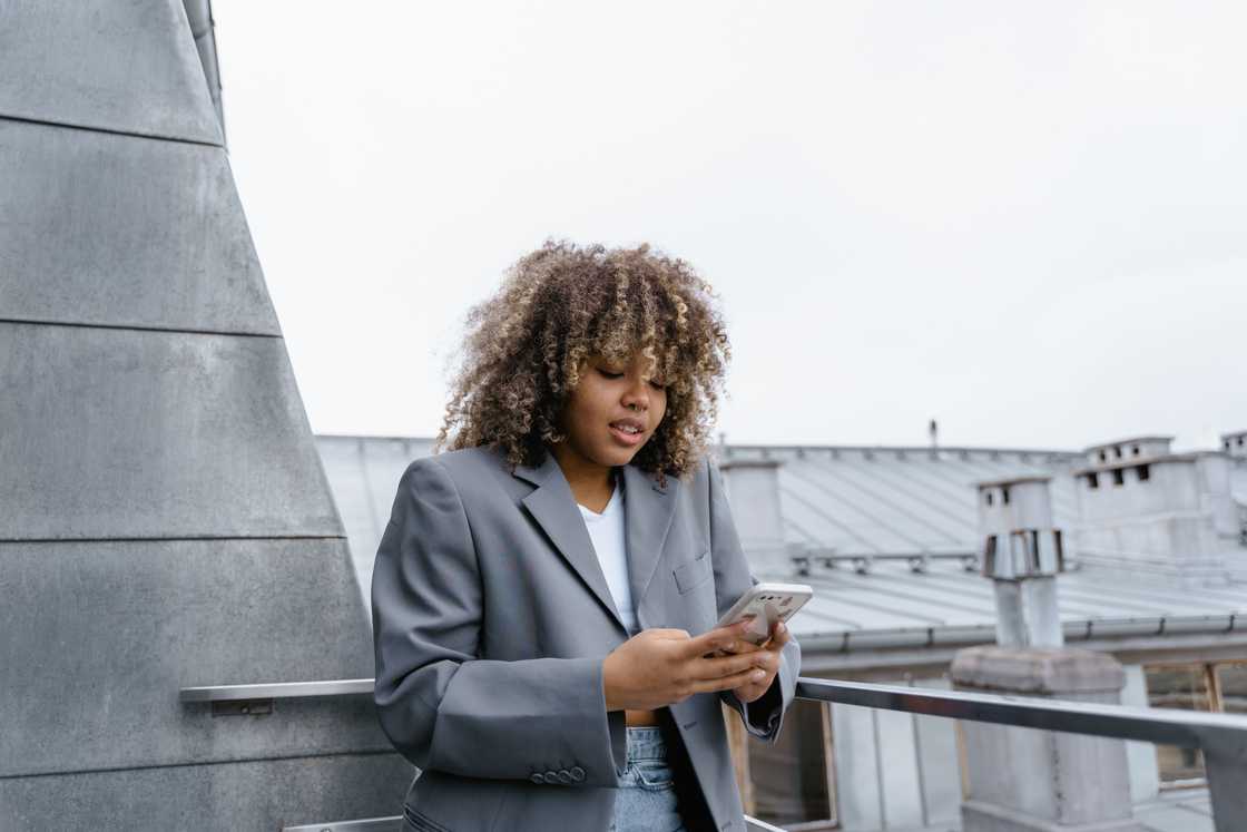 A woman in a grey jacket is using a smartphone A woman in a grey jacket is using a smartphone