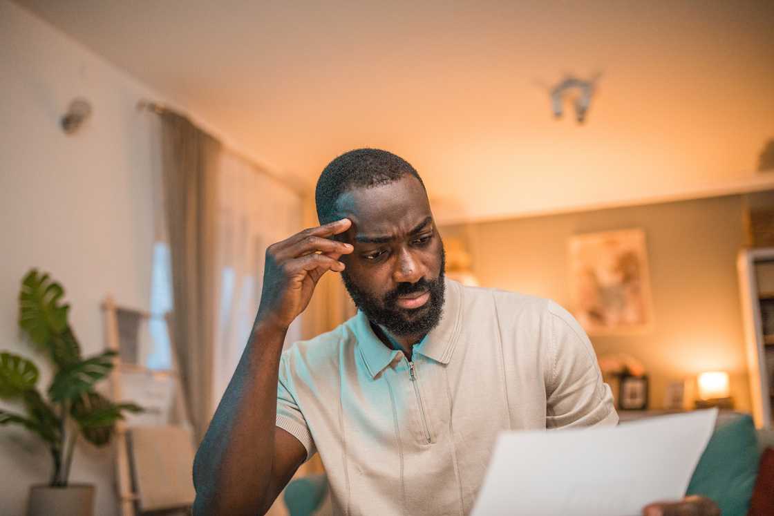A man staring at a document while sitting on the sofa A man staring at a document while sitting on the sofa