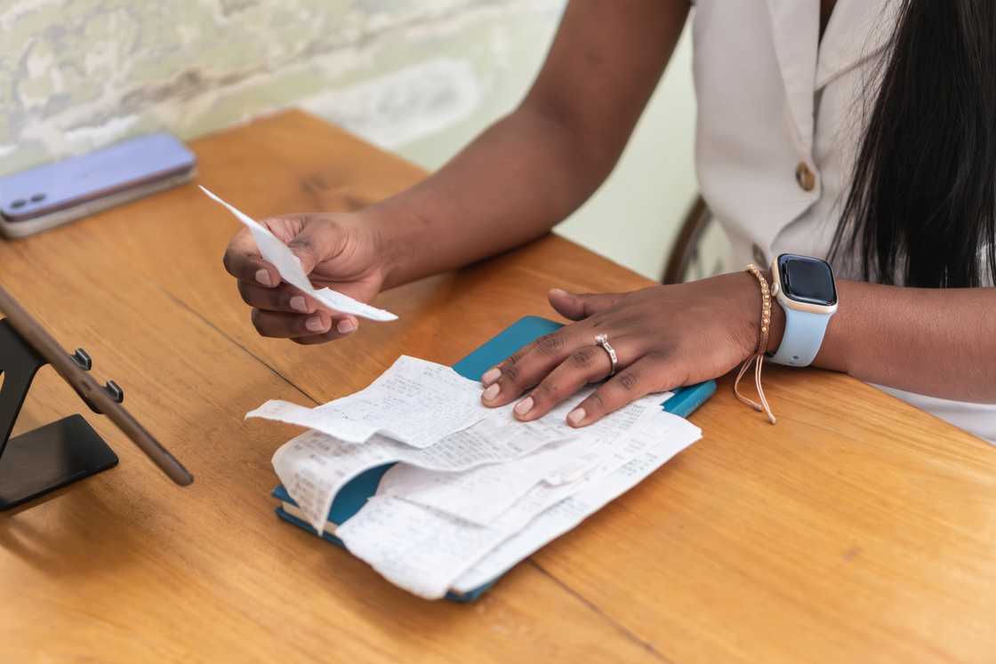 A woman reviews receipts and financial documents at a desk. A woman reviews receipts and financial documents at a desk.