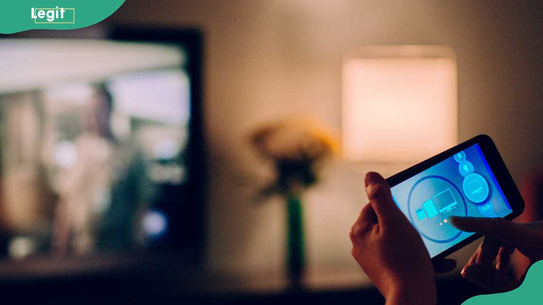 A person trying to connect a phone to a TV