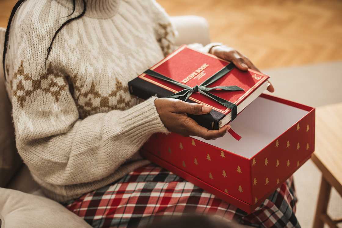 A person removes a novel from a neat present box.