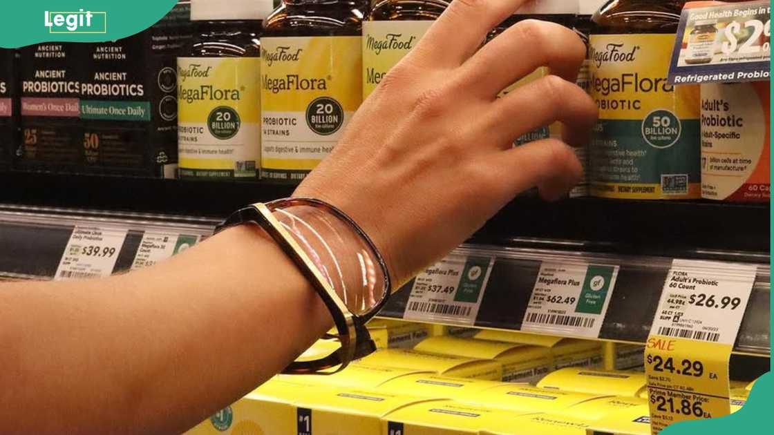 A person's hand with an EyeWris band on the wrist picks a product from a shelf